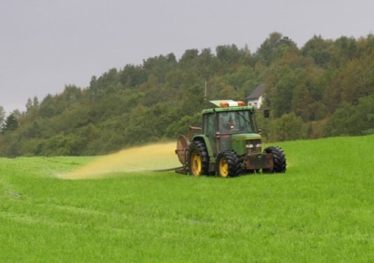 Grå himmel, grønne trer, traktor, grønt gras
