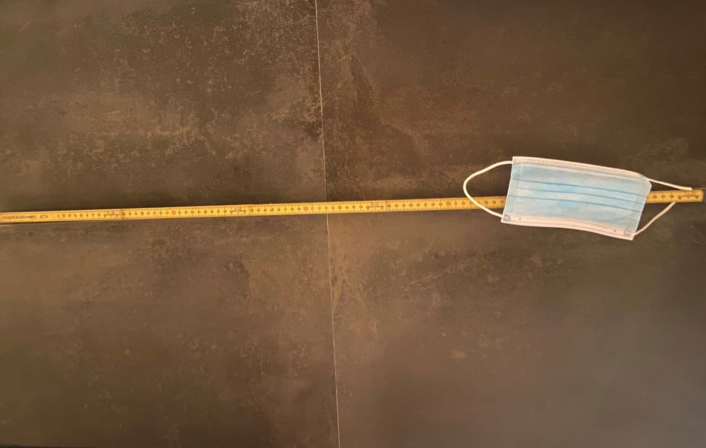 Illustrasjonsfoto av munnbind som ligger på bakken oppå en meterstokk