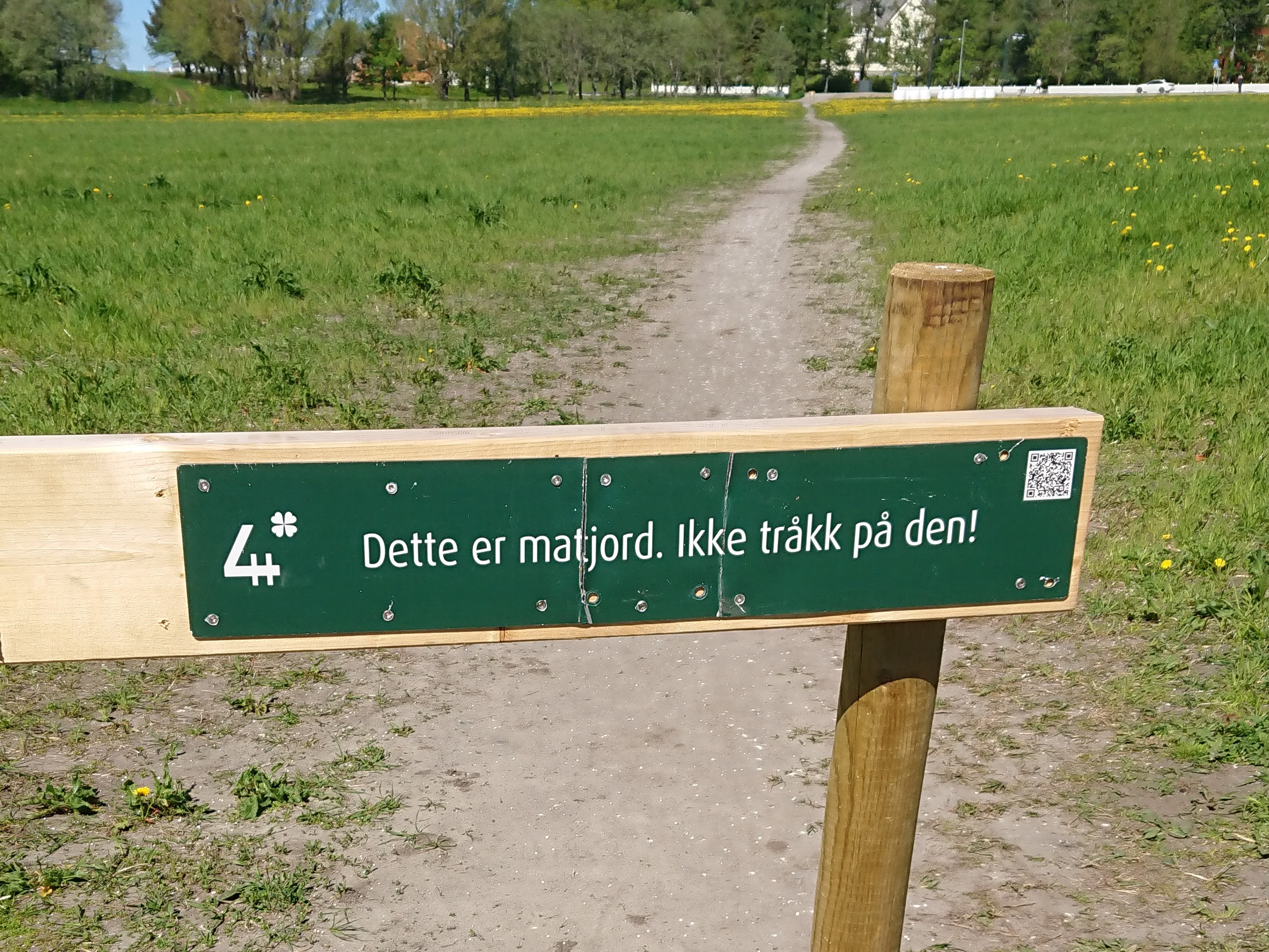 Ødelagt og reparert skilt ved sti over matjord på Langjordet i Bodøsjøen, Bodø.
